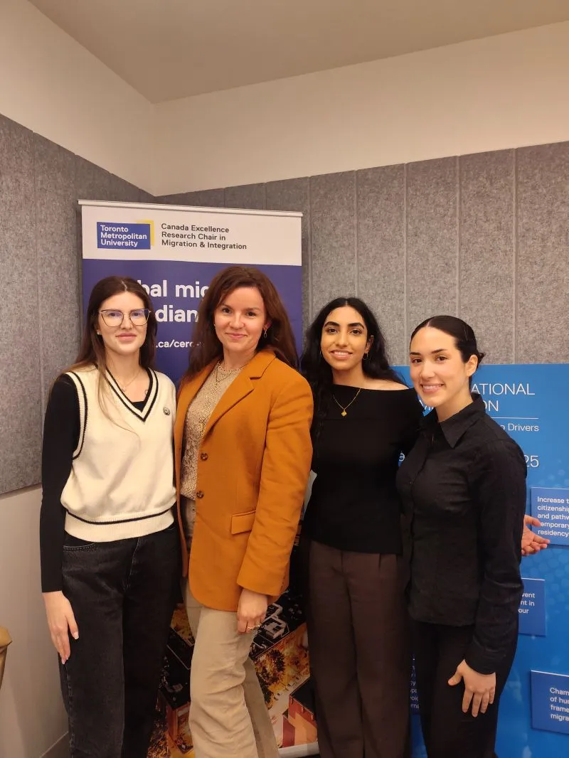 Four people in front of a Toronto Metropolitan University banner for the Canada Excellence Research Chair in Migration and Integration.