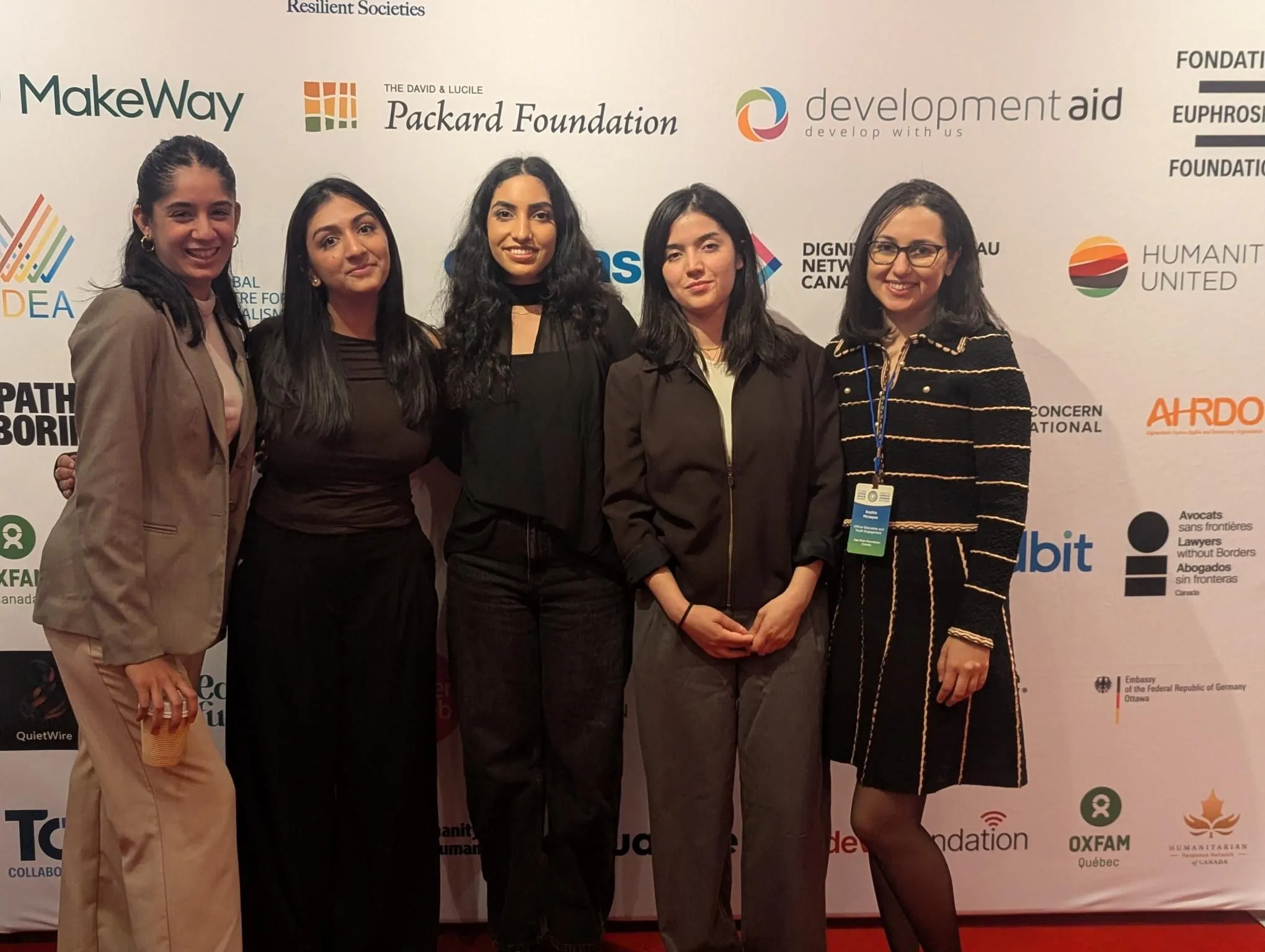 Five delegates, including Mishika Khurana at centre, in front of a sponsor wall at the Ottawa Civic Space Summit.